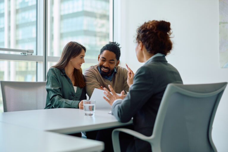 Happy couple reading terms of  agreement during  meeting with bank manager in office